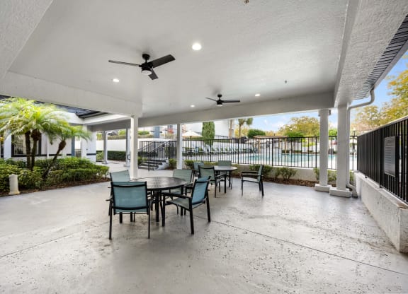 a patio with a table and chairs and a ceiling fan
