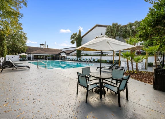 a swimming pool with a patio with chairs and an umbrella