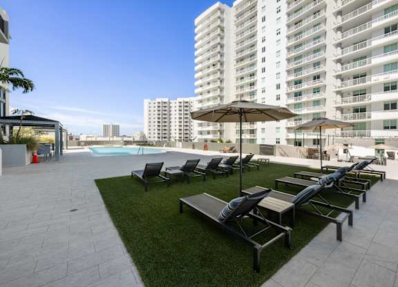 A large white building with a pool and lounge chairs.