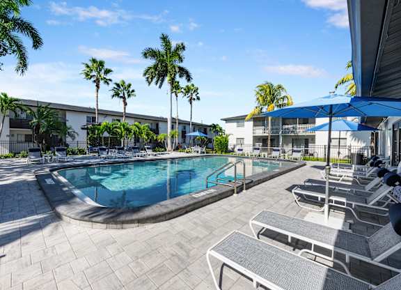 a swimming pool with chairs and umbrellas in front of a building