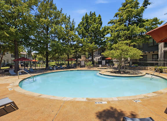 A small pool surrounded by trees and a building.