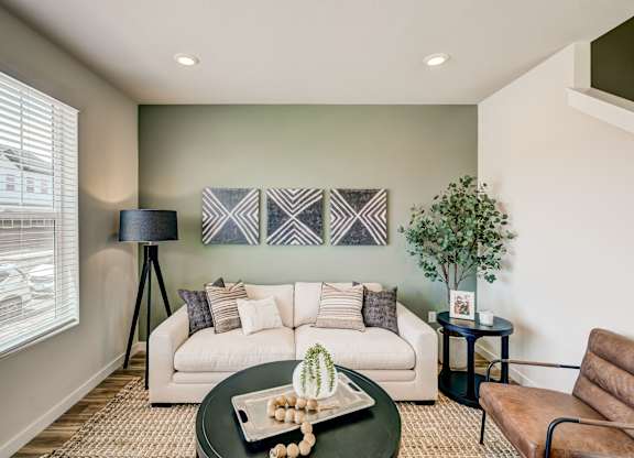 A living room with a white couch, a green table, and a brown chair.