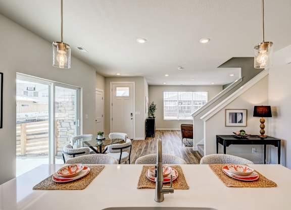 A modern dining room with a long table set for a meal.