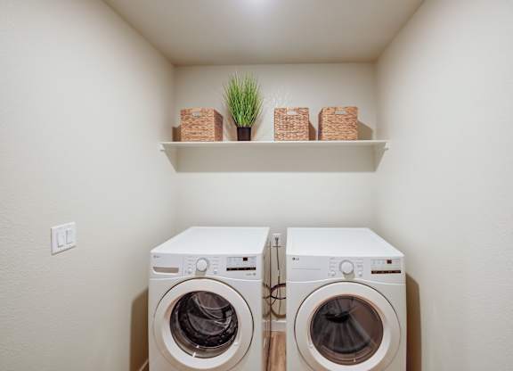 Two white front load washing machines in a small laundry room.