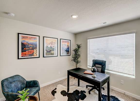 A room with a desk, chair, and pictures on the wall.