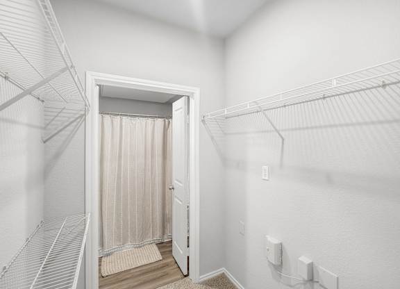 A white closet with a doorway leading to a bathroom.