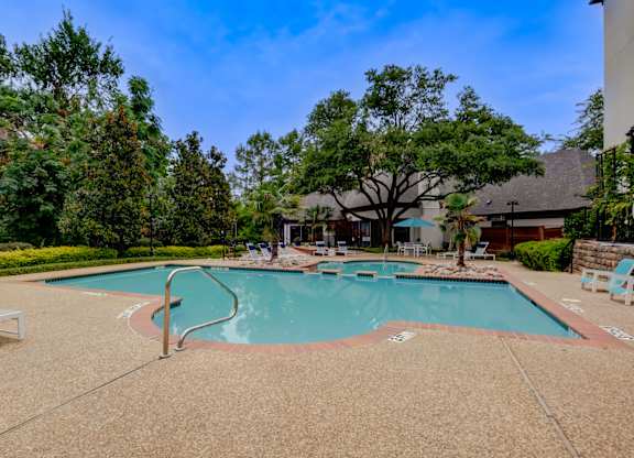 a swimming pool with trees and a building in the background