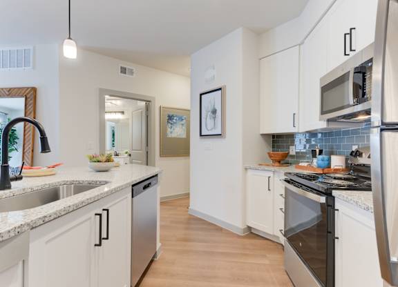 a kitchen with white cabinets and granite counter tops and stainless steel appliances