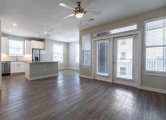 A spacious kitchen and living room with wood flooring and white walls.