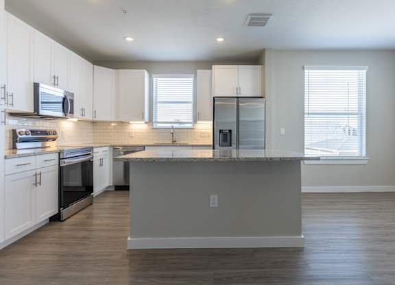 A kitchen with white cabinets and a grey island.