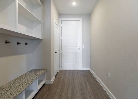 A hallway with a bench and a door.