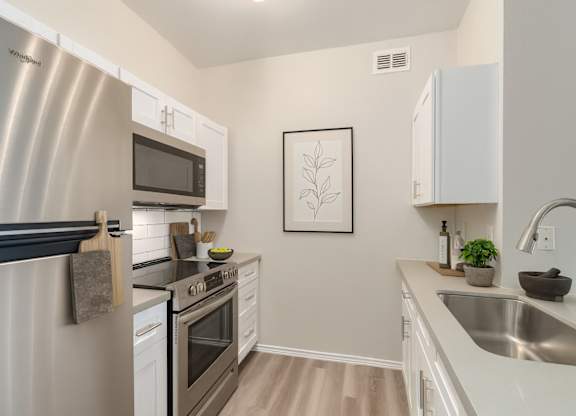 A modern kitchen with a stainless steel refrigerator and white cabinets.
