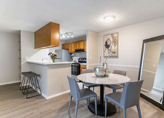 A kitchen with a bar and a dining table with chairs.