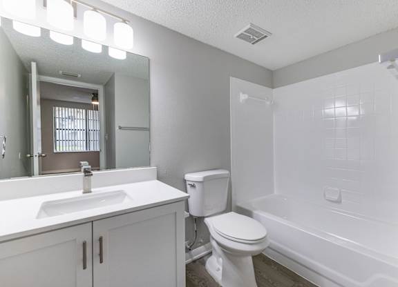 A white bathroom with a toilet, sink, and bathtub.