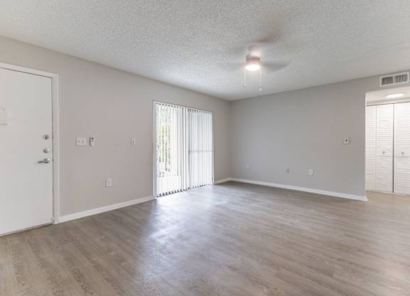 A spacious room with a sliding glass door and a ceiling fan.