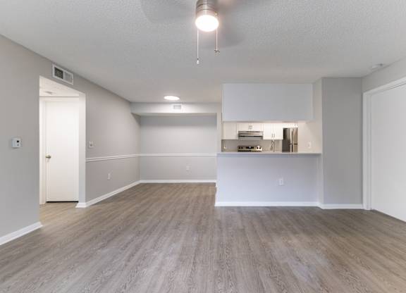 A spacious room with a kitchenette in the background.