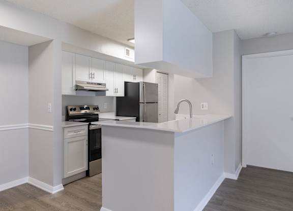 A kitchen with white cabinets and a black refrigerator.