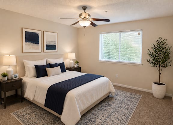 A bedroom with a bed, a ceiling fan, and a window.