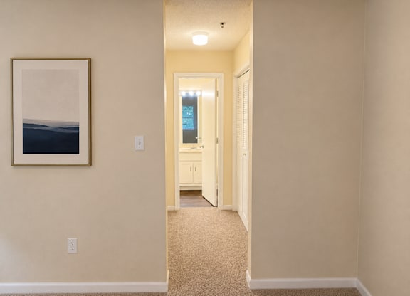 A hallway with a painting on the wall and a door at the end.