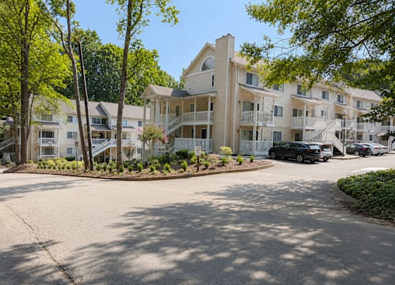 A sunny day at a residential complex with a black car parked in the driveway.