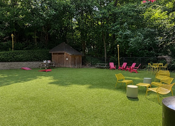 A backyard with a lawn, chairs, and a gazebo.