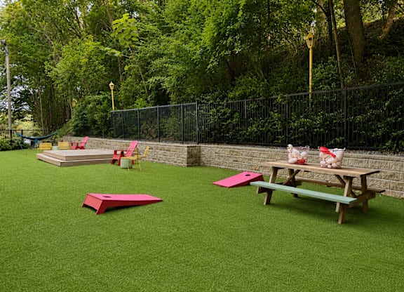 A playground with a green surface and a picnic table.