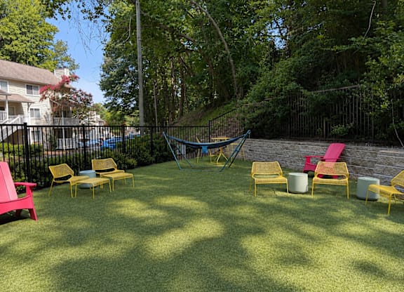 A backyard with a hammock, lawn chairs, and a trampoline.
