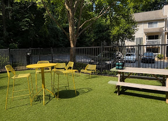 A yellow table and chairs are set up on a green lawn.