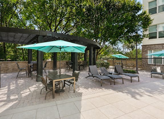 A patio with a table and chairs under a green umbrella.