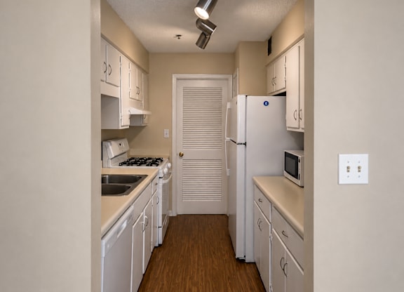 A kitchen with white appliances and cabinets.