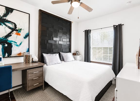 A bedroom with a bed, desk, and chair.
