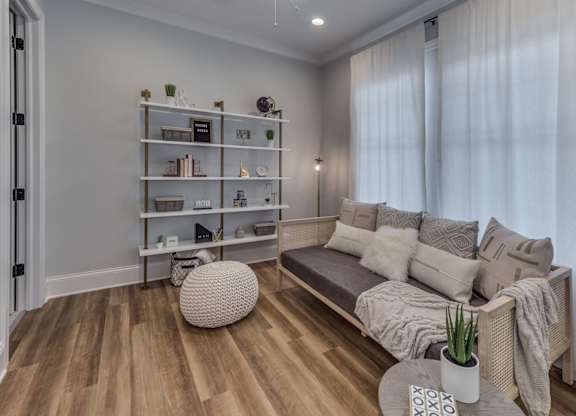 A modern builder grade bedroom staged as an office with a couch.