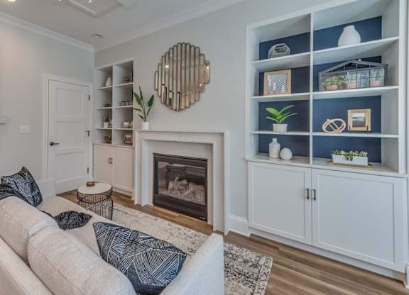 A modern builder grade living room with a fireplace surrounded by custom build ins and white couch.
