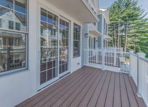 A wooden deck with a white railing with a sliding door right off the kitchen/dining room.