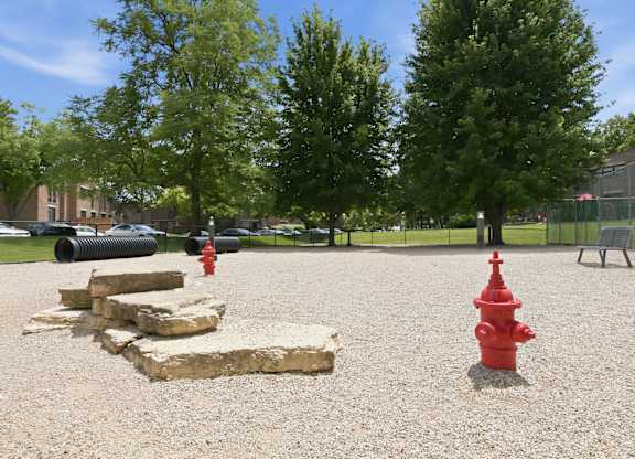 A red fire hydrant stands in the middle of a gravel area.