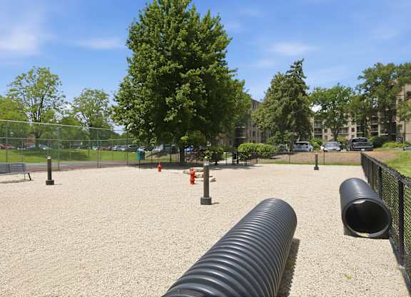A playground with a large black tube in the foreground.