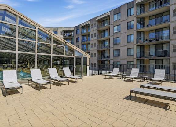 A sunny day at the rooftop pool with lounge chairs and a glass enclosure.