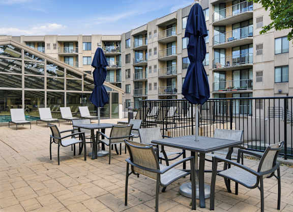 A patio with a table and chairs and umbrellas.