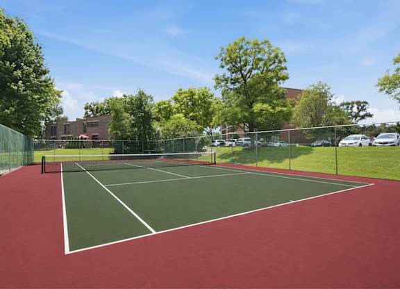 A tennis court with a red surface and white lines.