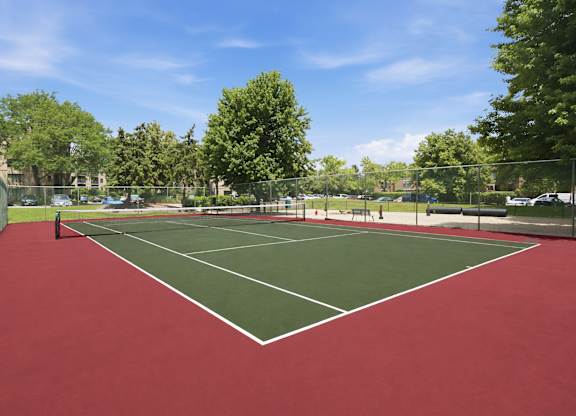 A tennis court with a red surface and white lines.