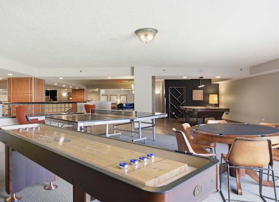 A billiard table is in the middle of a room with chairs and a bar.