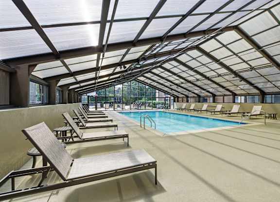 A sunroom with a pool and lounge chairs.