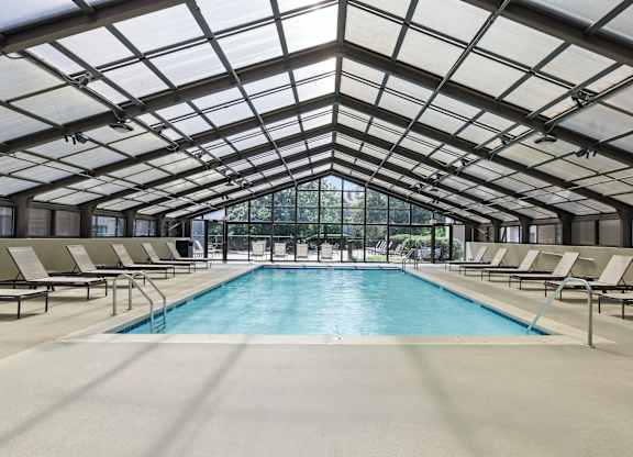 A large indoor swimming pool with sunroof and lounge chairs.