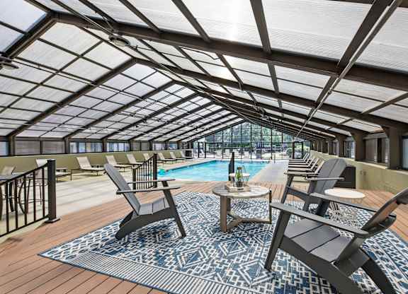 A sunroom with a pool and lounge chairs.