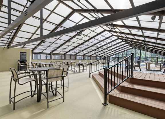 A glass-roofed patio with tables and chairs.