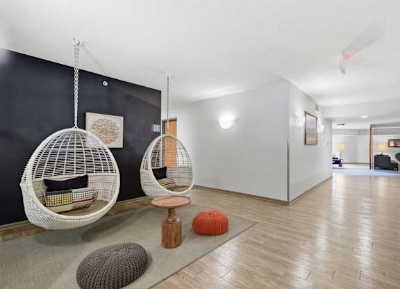 A room with two hanging chairs and a rug.