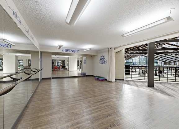 A spacious room with wooden floors and a large mirror on the wall.
