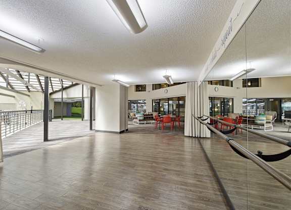 A spacious room with wooden floors and a long mirror on the wall.