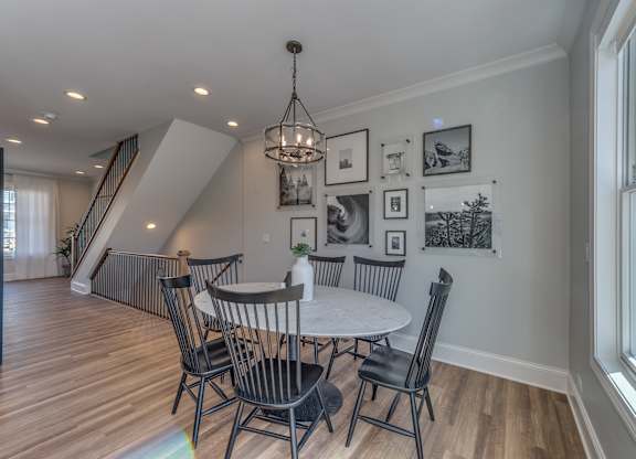 A modern builder grade dining room with a table and chairs.