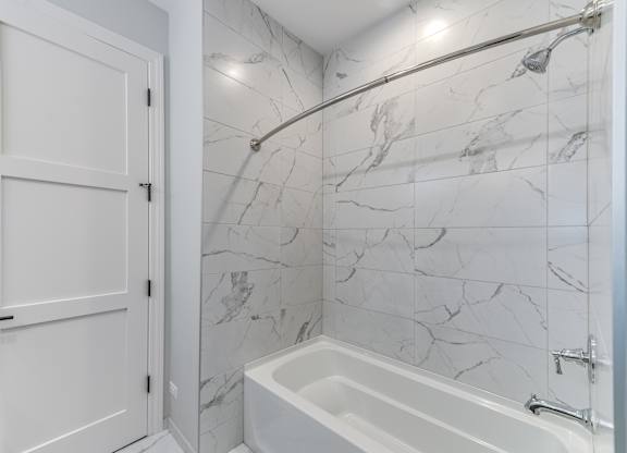 A modern builder grade bathroom with a marble tile shower and tub.
